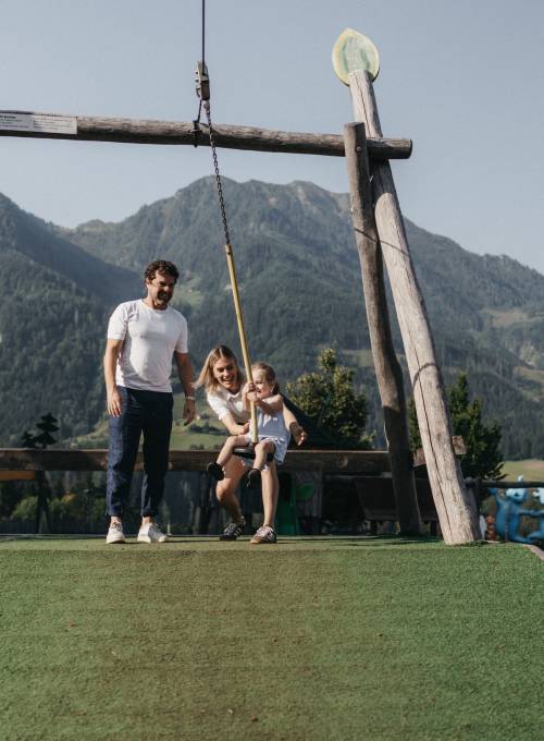 Eine Familie am Funcourt vor dem Familienhotel Alpina Alpendorf.