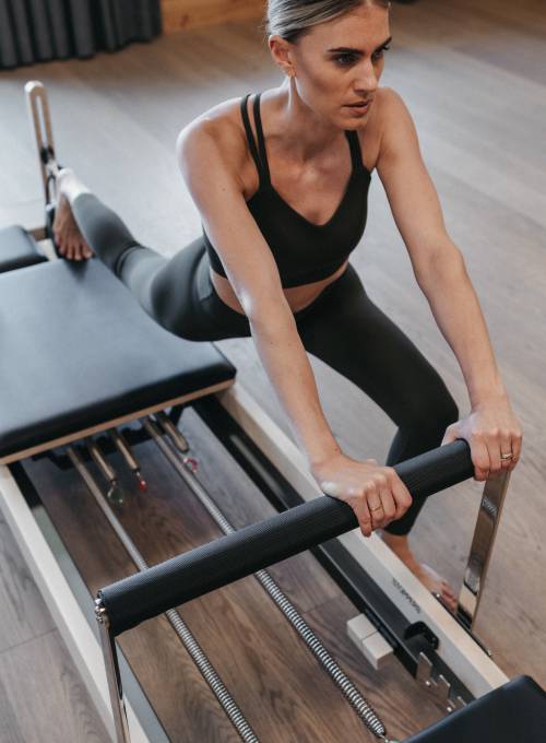 Eine Frau beim Reformer Pilates Retreat im Alpina Alpendorf in Salzburg. 