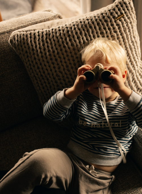 A girl is painting a picture in the childcare facility at Alpina Alpendorf.