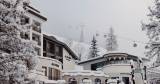 Die moderne Fassade des Hotel Alpinas im Winter mit der Gondel im Hintergrund.