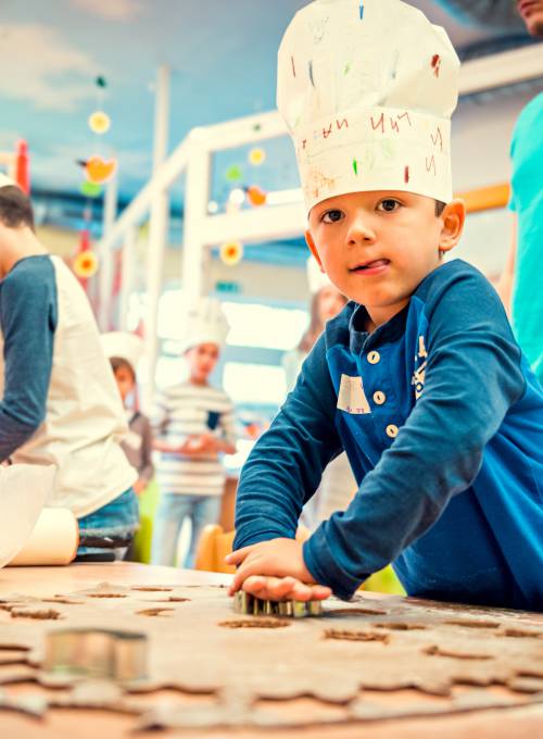 A girl is painting a picture in the childcare facility at Alpina Alpendorf.