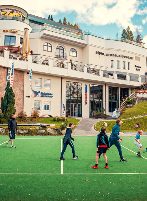 Auf dem großen Erlebnisspielplatz spielen ein paar Jungs Fußball. 