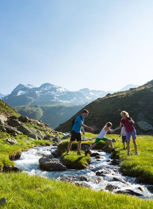 Eine Familie wandert an einem Bach in ihrem Sommerurlaub im Salzburger Land. 