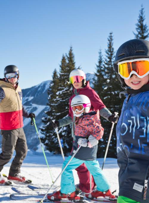 Zwei Erwachsene verbringen ihren Skiurlaub mit ihren Kindern in Österreich. 