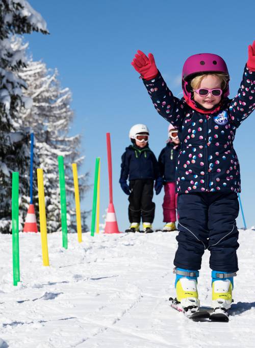Ein Mädchen hat die ersten Erfolge beim Skifahren in der Kinder-Skischule im Alpendorf. 