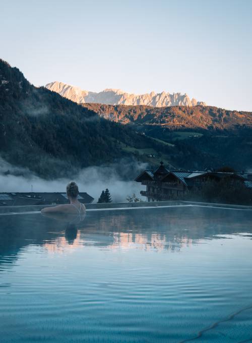 Eine Frau genießt ein Bad im Infinity Pool des Alpina Family, Spa und Sporthotels. 