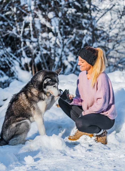 Eine Frau verbringt ihren Urlaub mit ihrem Hund im Salzburger Land im Schnee.