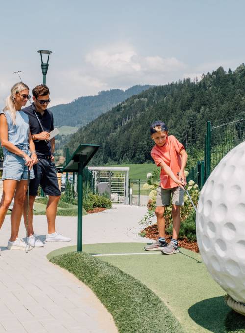 Eine Familie spielt Minigolf am OPEN Golf St.Johann.  