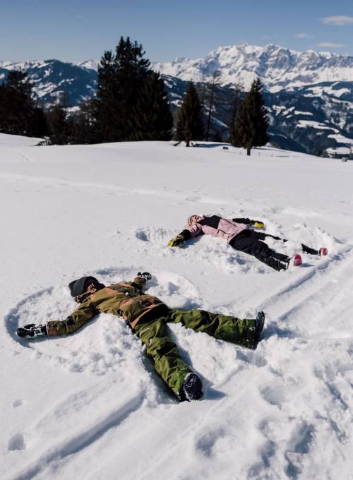 Eine Familie spielt im Schnee während ihres Ski-Urlaubs im Salzburger Land.  
