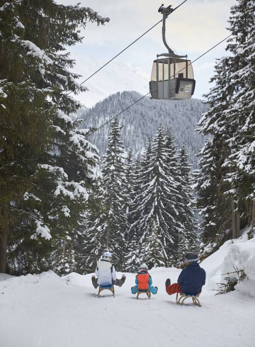 Eine Familie auf dem Schlitten während ihrem aufregenden Familienurlaub im Salzburger Land.