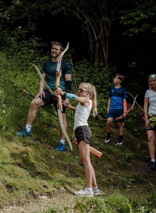 In ihrem Familienurlaub im Salzburger Land füttern drei Schwestern eine Ziege mit Heu.