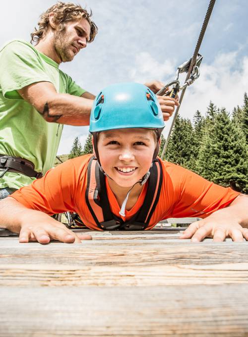 Ein Junge genießt den Familienurlaub im Salzburger Land im Woodland Waldseilgarten.