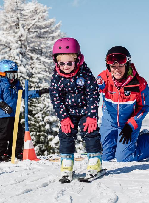 Ein Mädchen hat die ersten Erfolge beim Skifahren in der Kinder-Skischule im Alpendorf. 