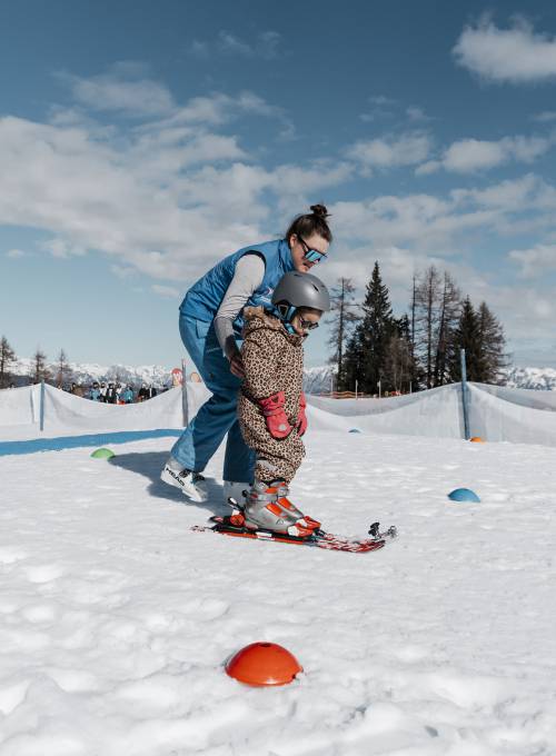 Ein kleines Mädchen lernt in der Skischule das Skifahren im Ski-Urlaub im Salzburger Land. 