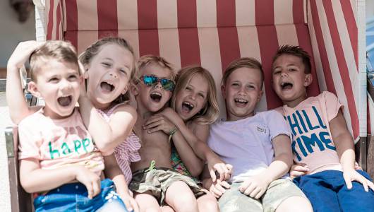 Kinder lachen in einem Standkorb im Hotel Alpina in St Johann.  