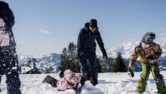 Eine Familie spielt im Schnee beim Winterurlaub im Alpina.